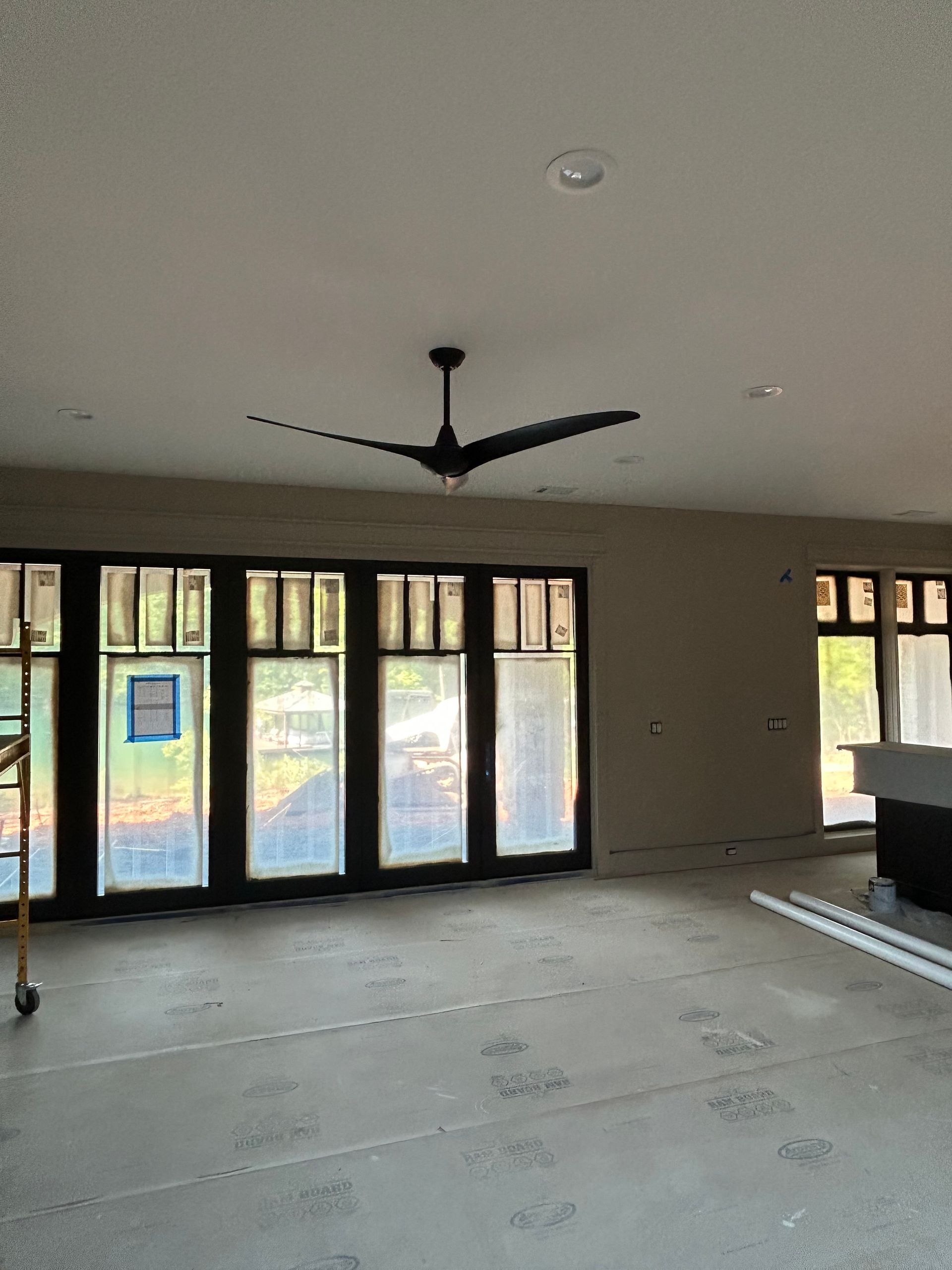 An empty room with a ceiling fan and lots of windows