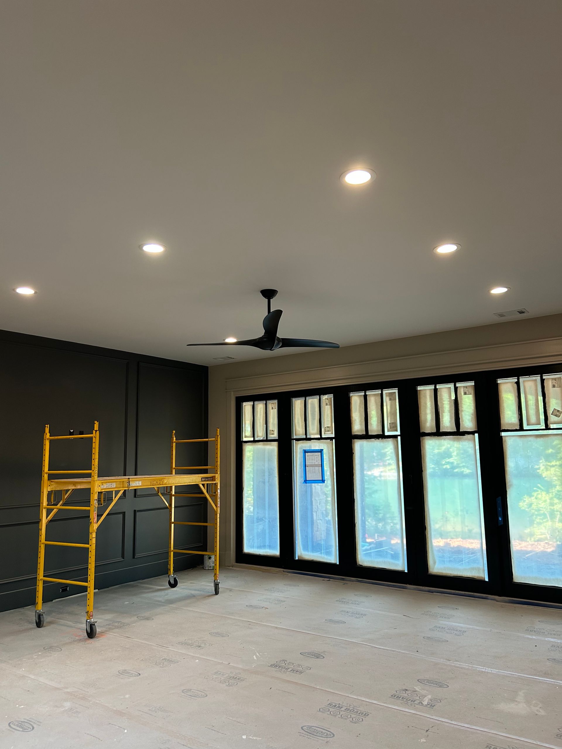 An empty room with a yellow scaffolding and a ceiling fan