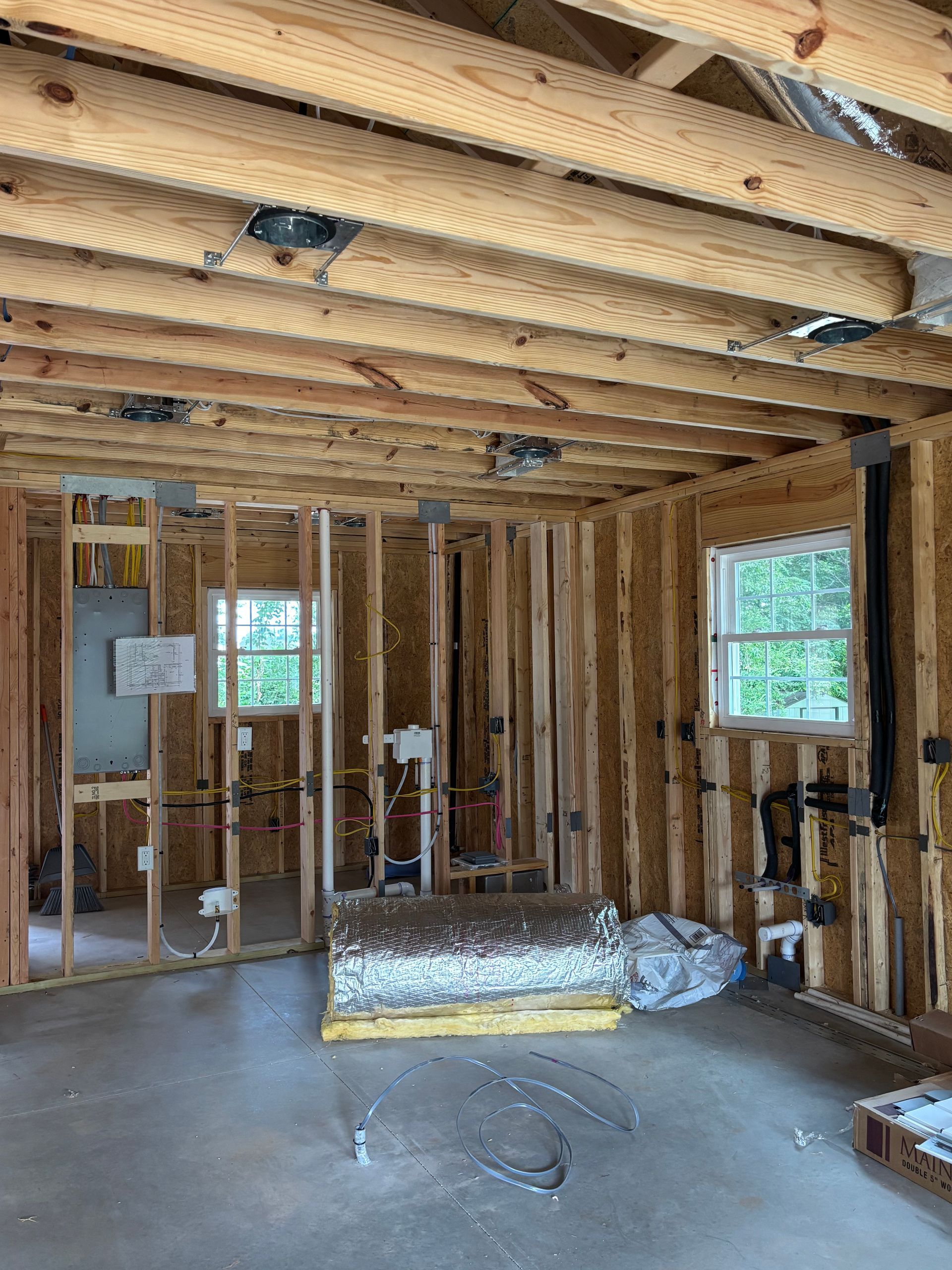 A room in a house under construction with wooden beams and windows.