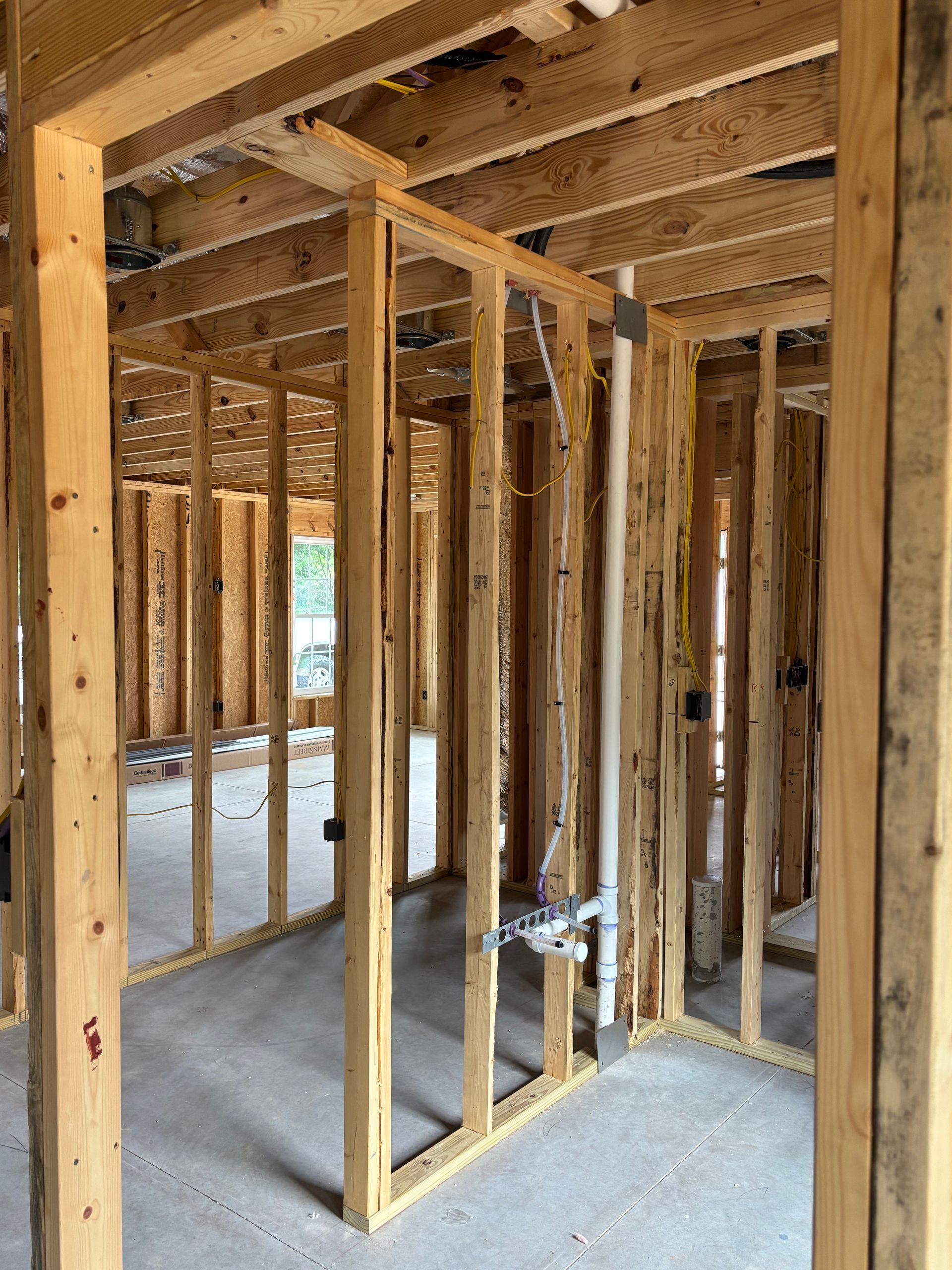 A room in a house under construction with wooden walls and pipes.