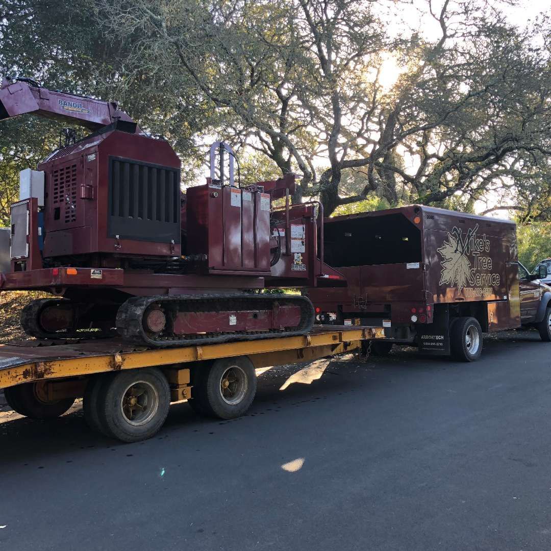 A large wood chipper on a trailer, attached to a truck, parked on a road.
