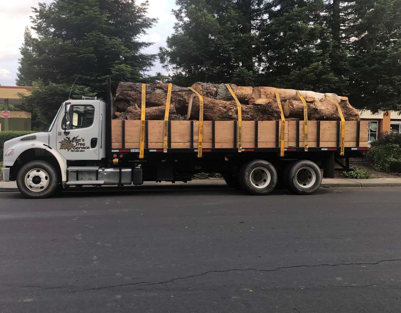 White truck loaded with tree bark, secured with straps, parked on a street. White truck loaded with tree bark, secured with straps, parked on a street.