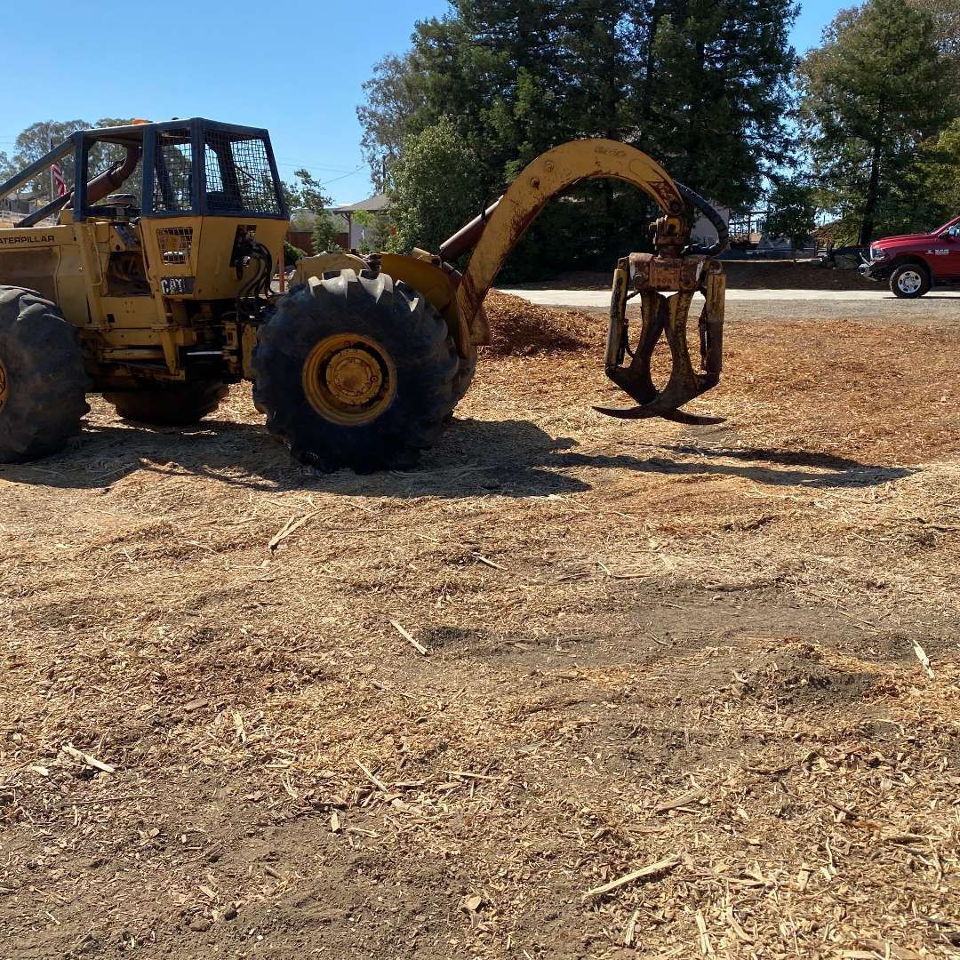 A yellow tractor is parked in a dry field
