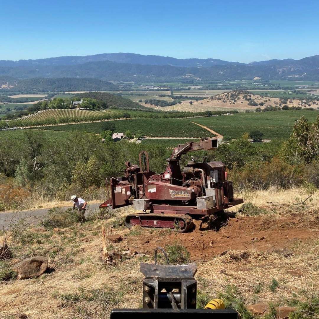A bulldozer is sitting on top of a dirt hill with mountains in the background. A bulldozer is sitting on top of a dirt hill with mountains in the background.