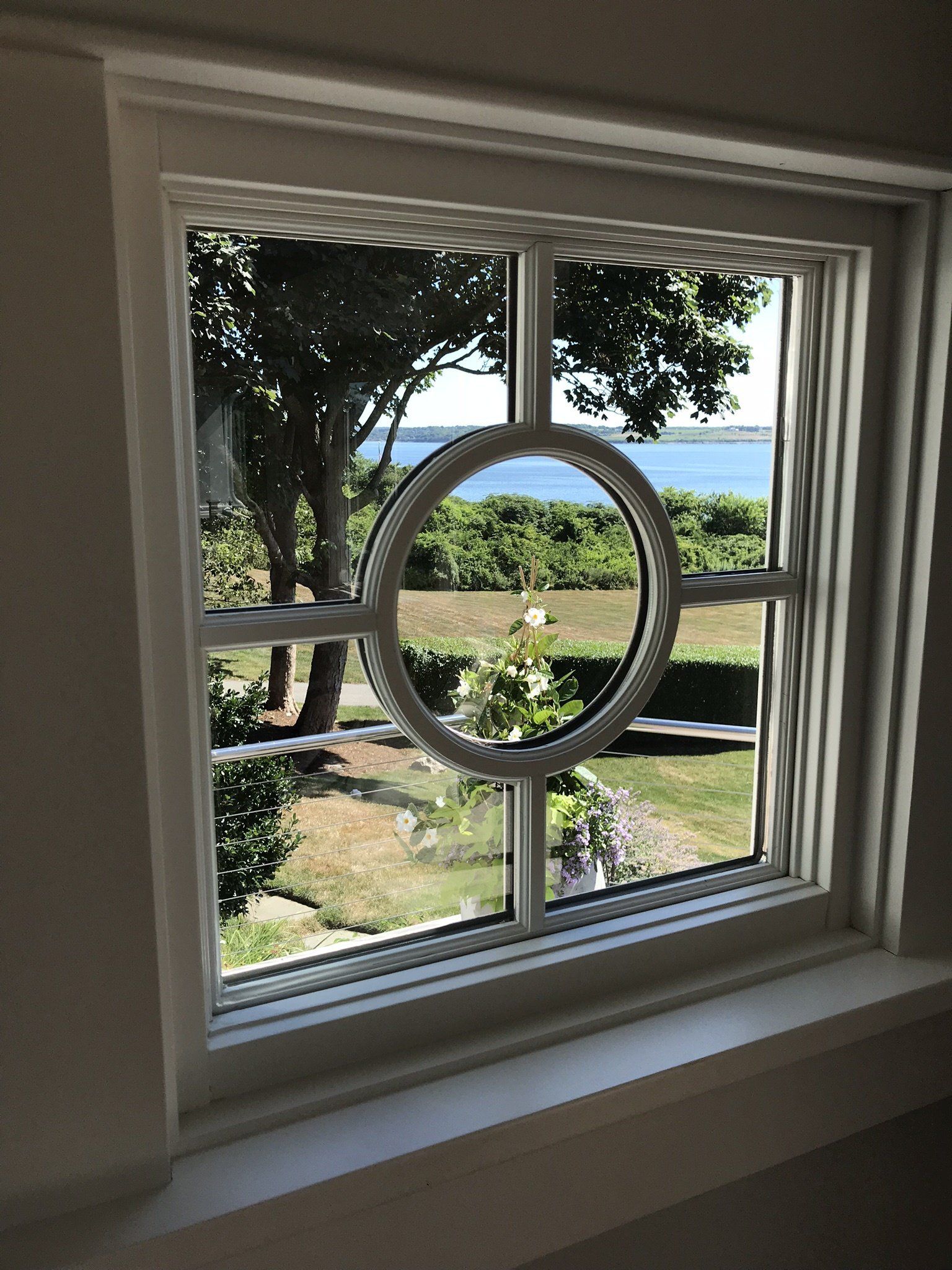 A window with a circular window frame looking out to the ocean.