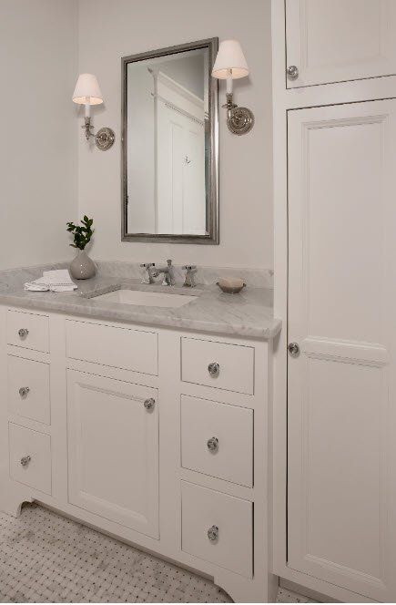 A bathroom with white cabinets a sink and a mirror