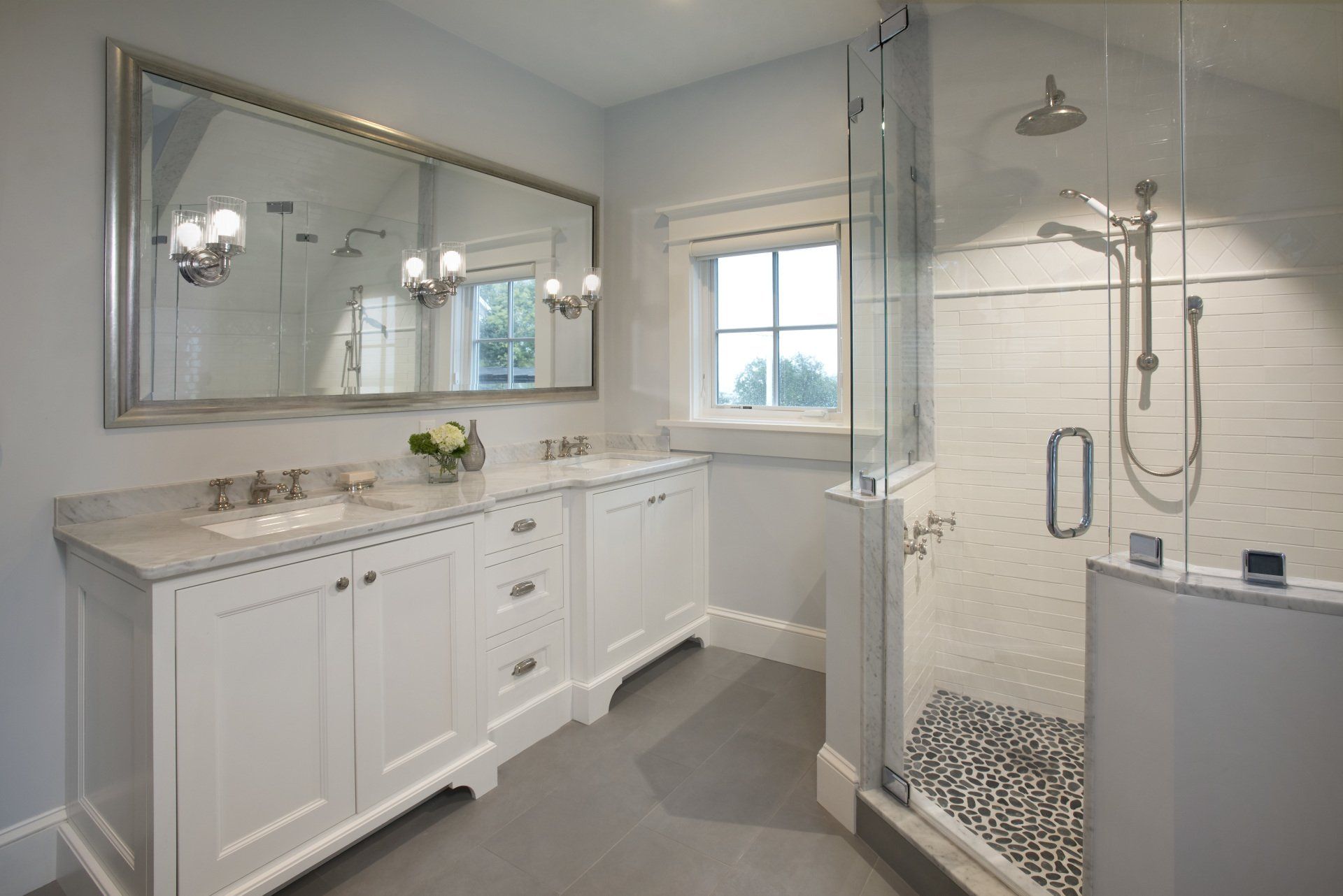 A bathroom with two sinks and a walk in shower.
