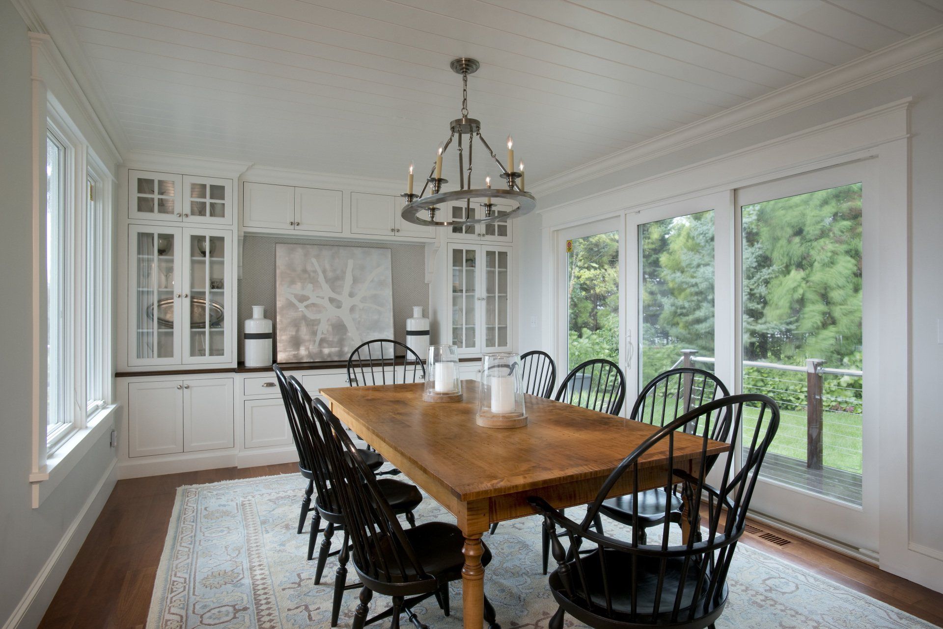 A dining room with a wooden table and chairs and a chandelier.