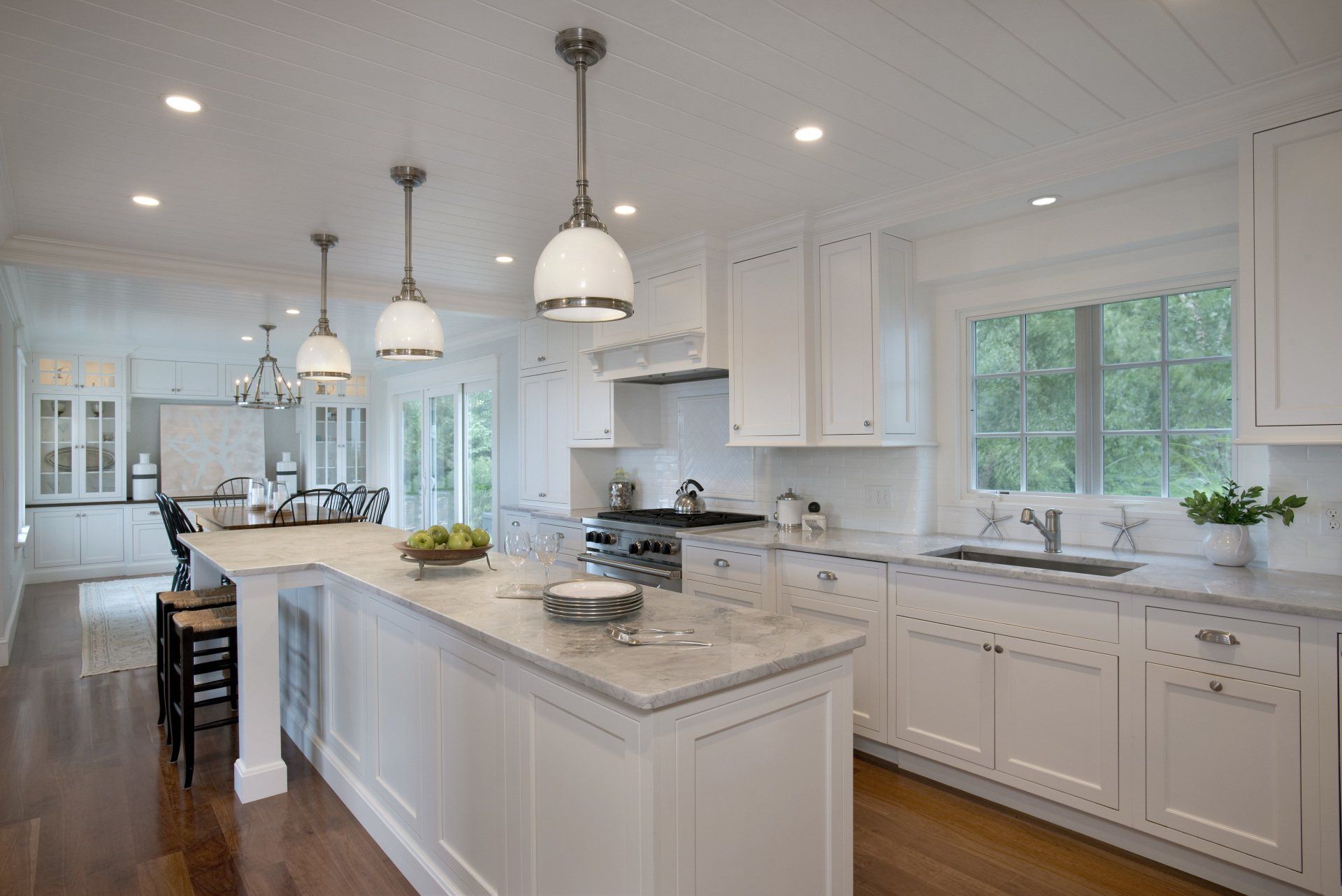 A kitchen with white cabinets , granite counter tops , and a large island.