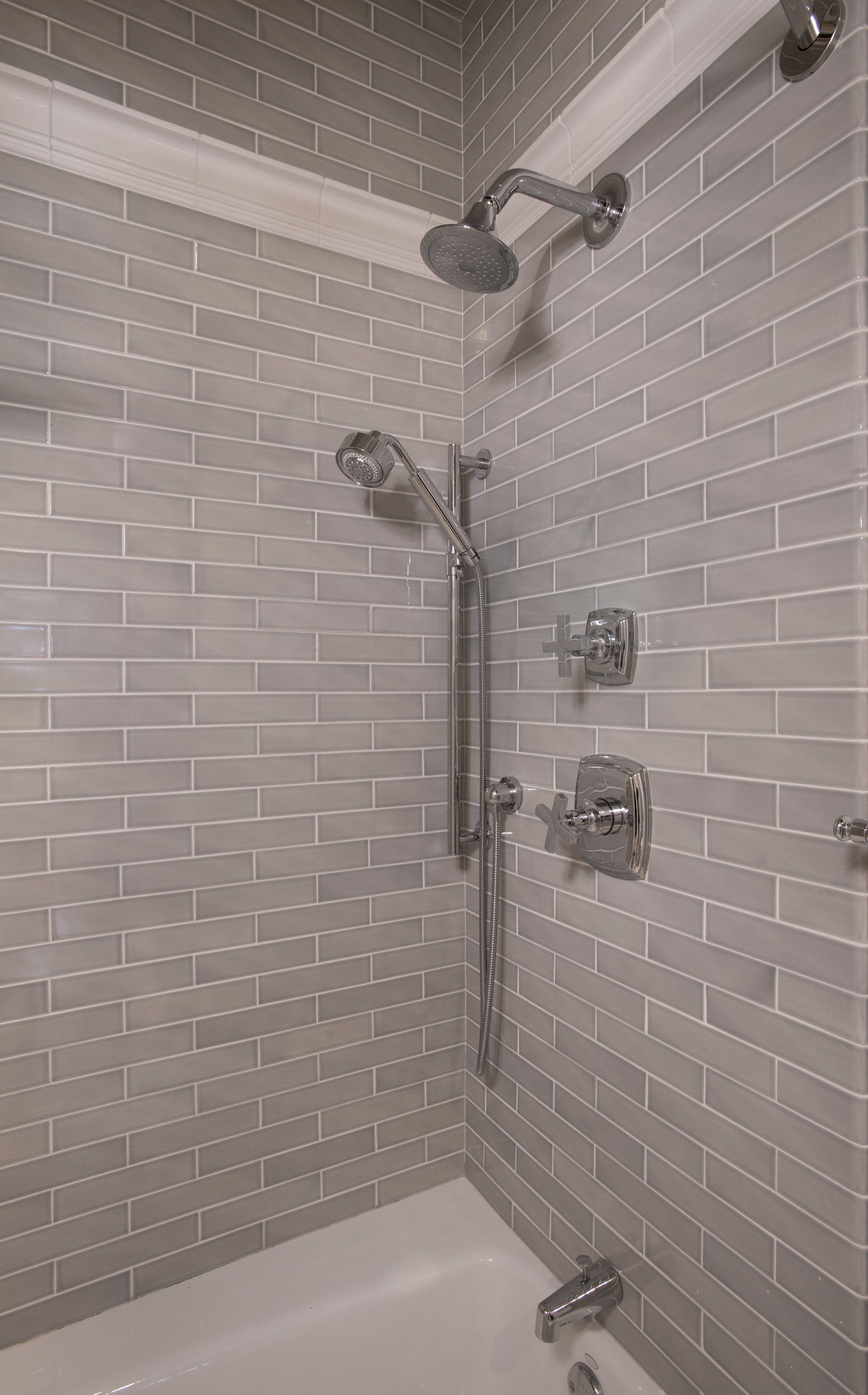 A bathroom with a bathtub , shower , and subway tile walls.