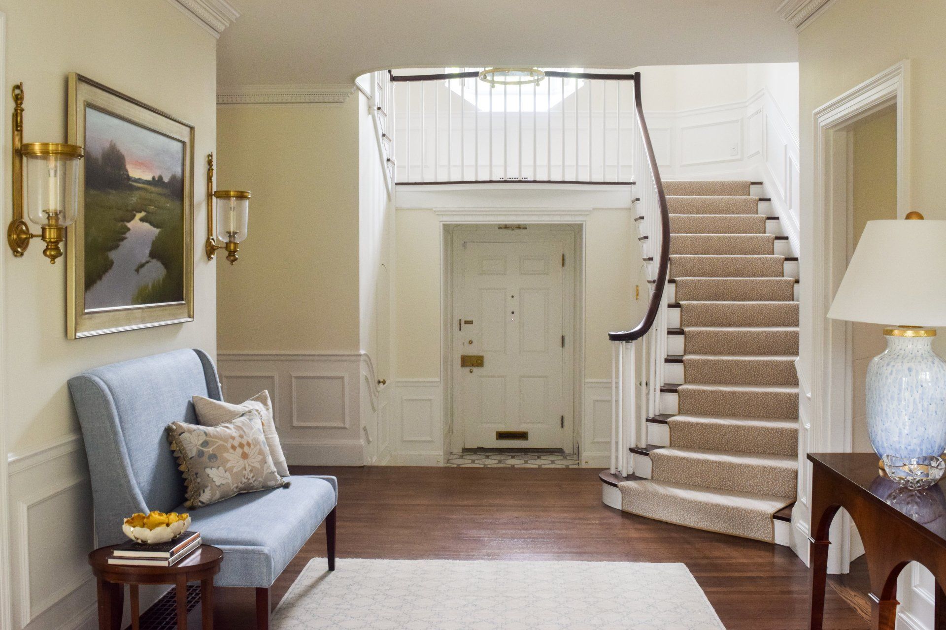 A hallway with a blue bench and stairs leading up to the second floor