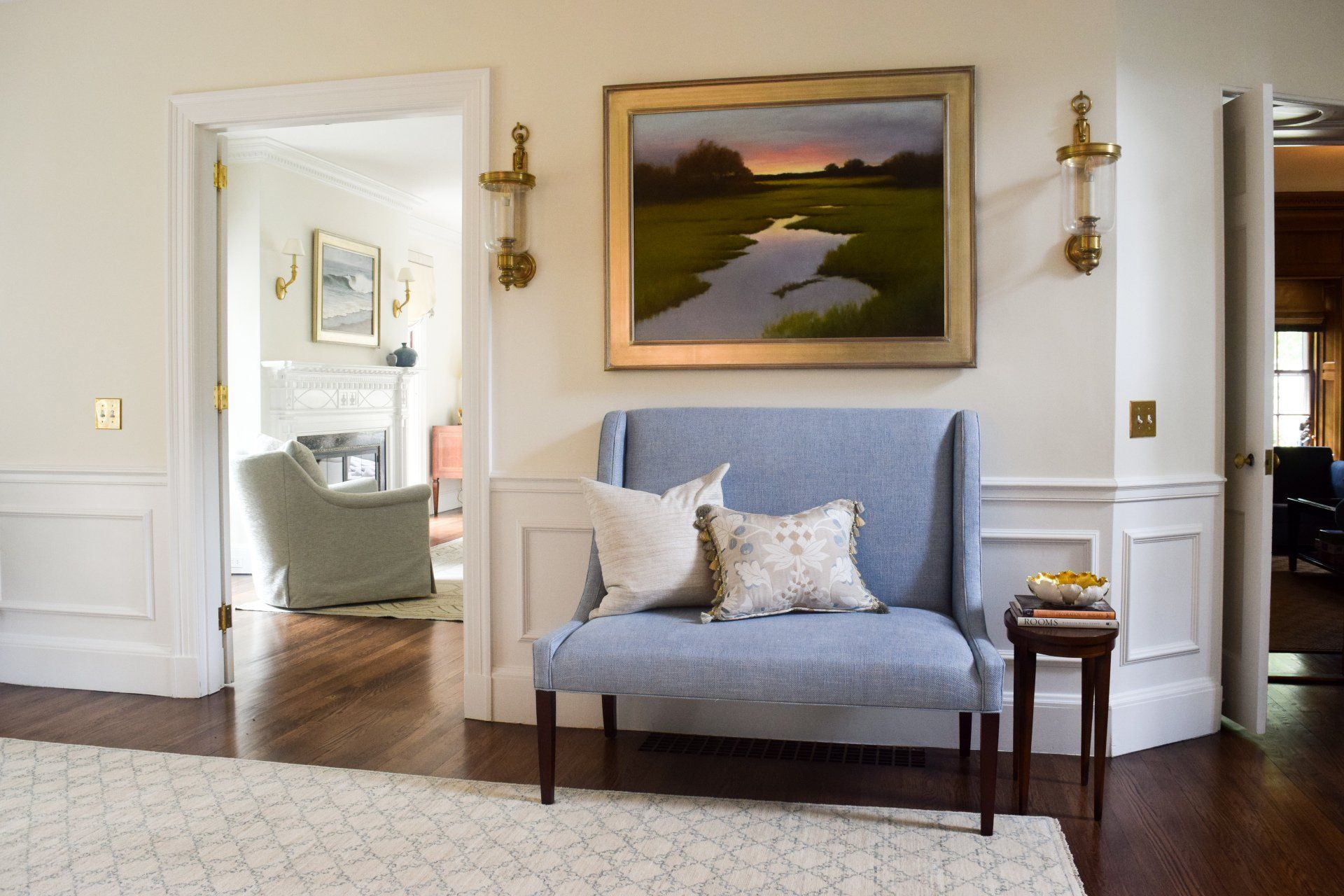 A living room with a blue bench and a painting on the wall.