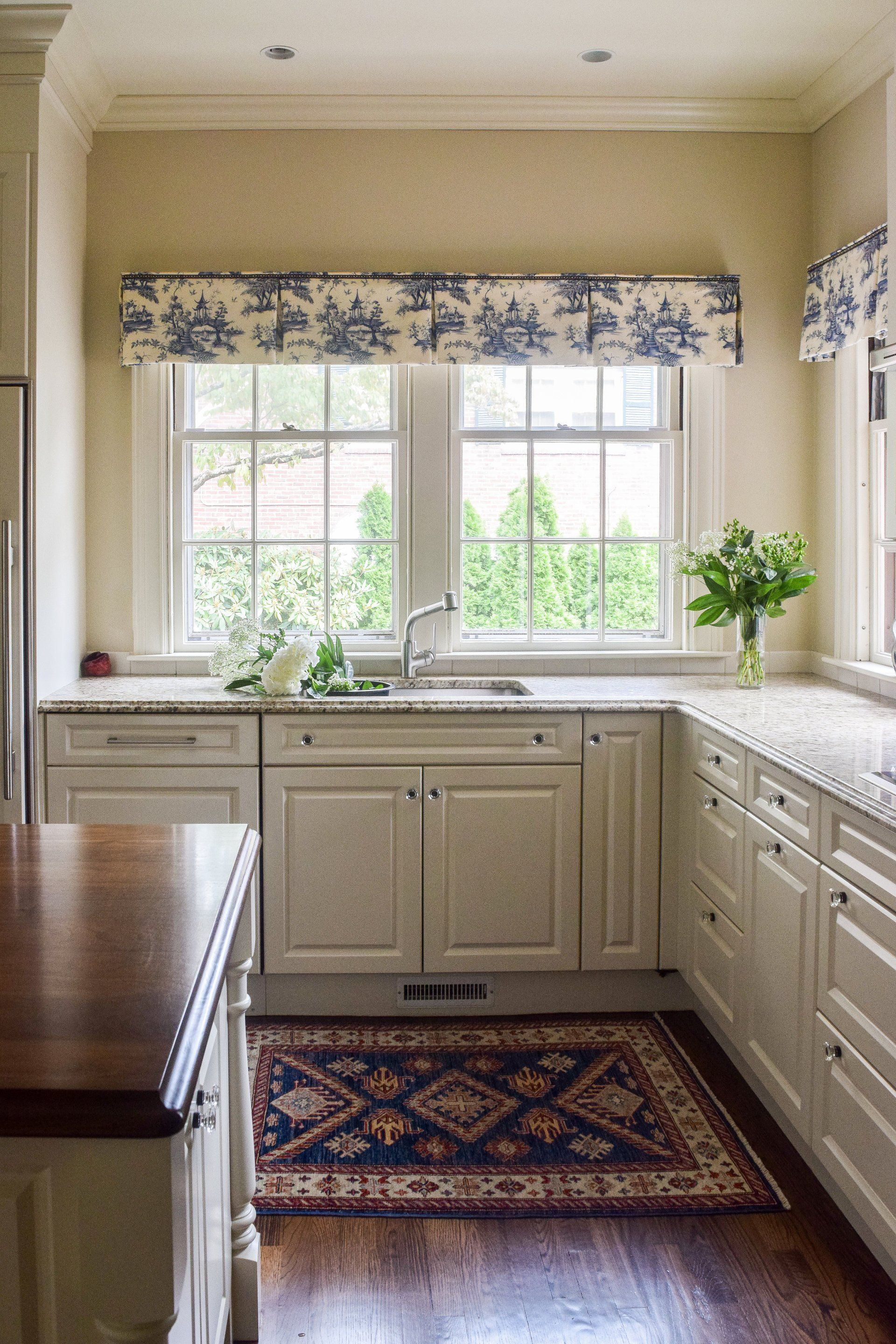 A kitchen with white cabinets and a rug on the floor
