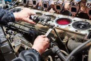 A man is working on a car engine with a wrench.