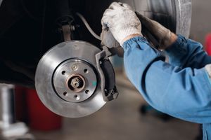 A mechanic is fixing a brake disc on a car in a garage.