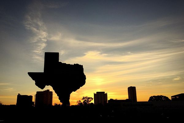 Texas silhouette against a sunset with a skyline.