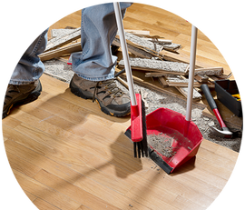 a person is cleaning a wooden floor with a broom and shovel .