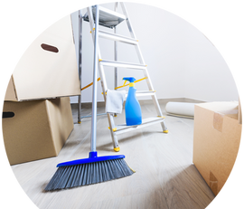 a room with boxes , a ladder , a broom and a spray bottle .