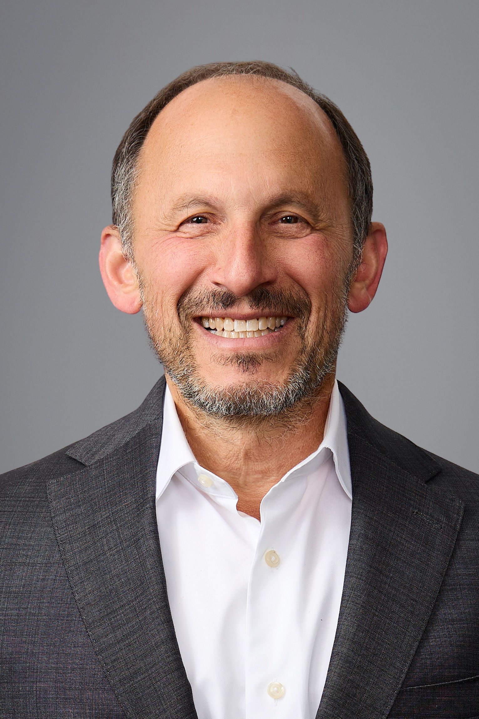 A man with a beard and a suit is smiling for the camera.