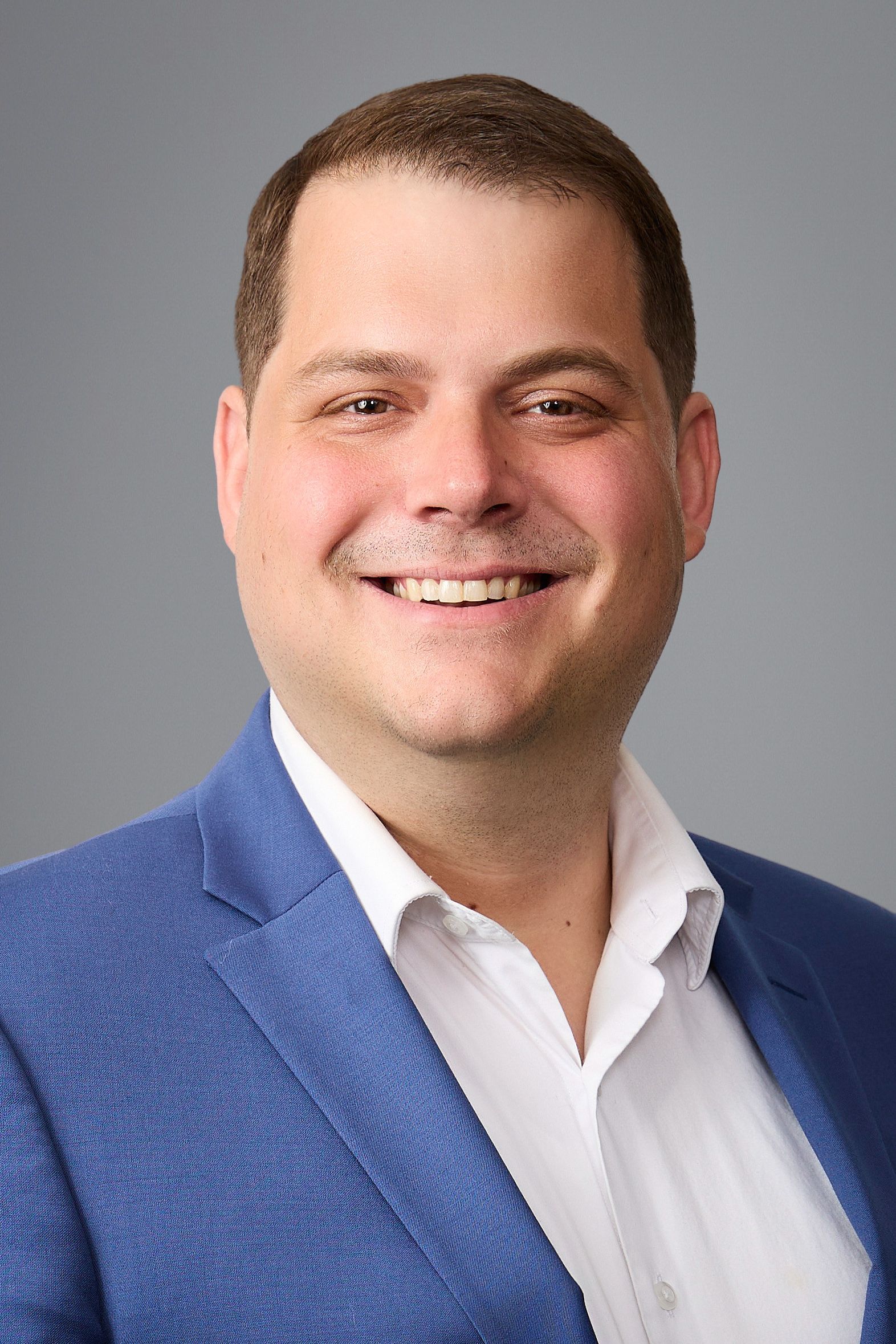 A man in a blue suit and tie smiles for the camera