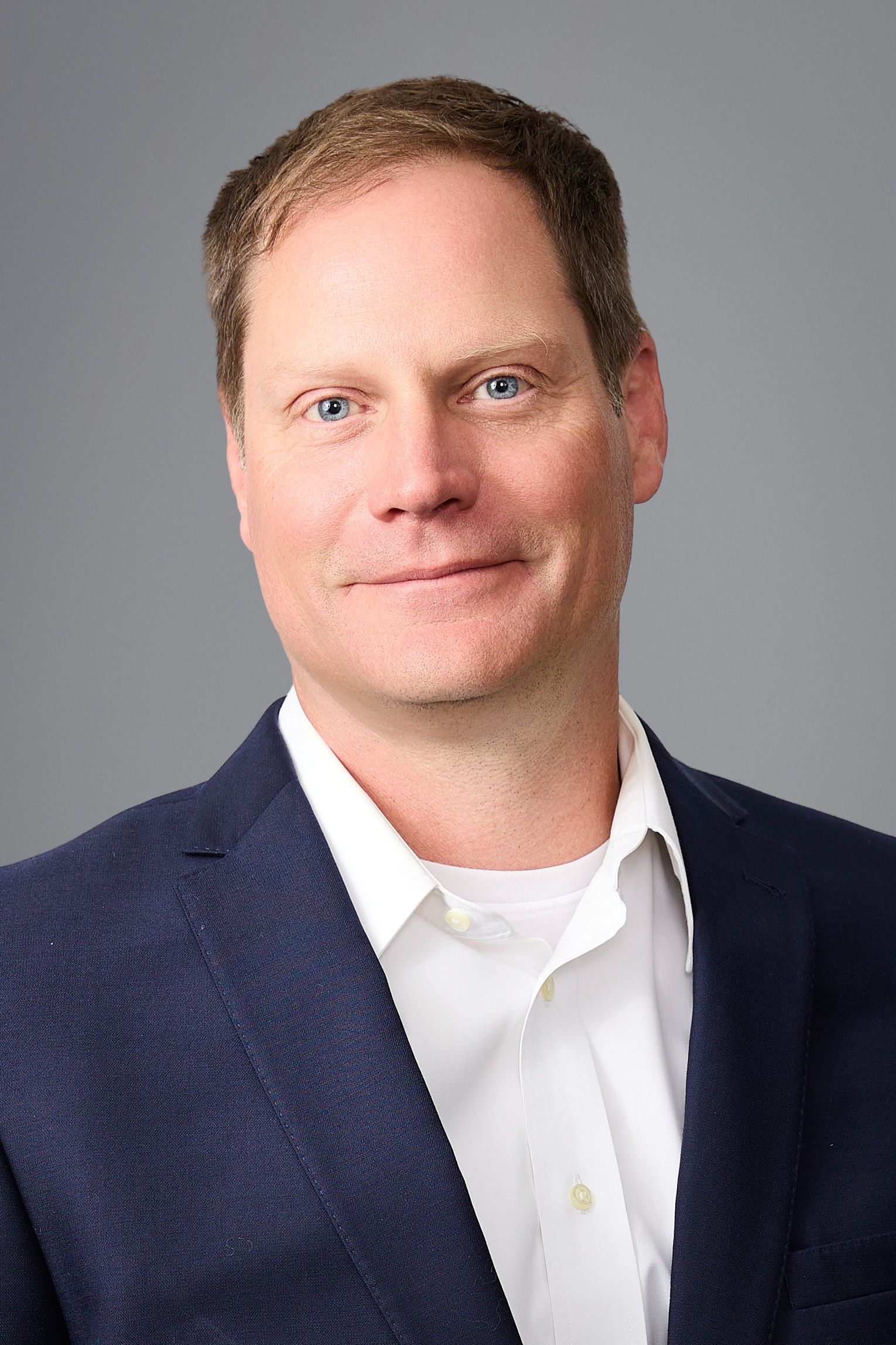 A man in a suit and tie is smiling for the camera