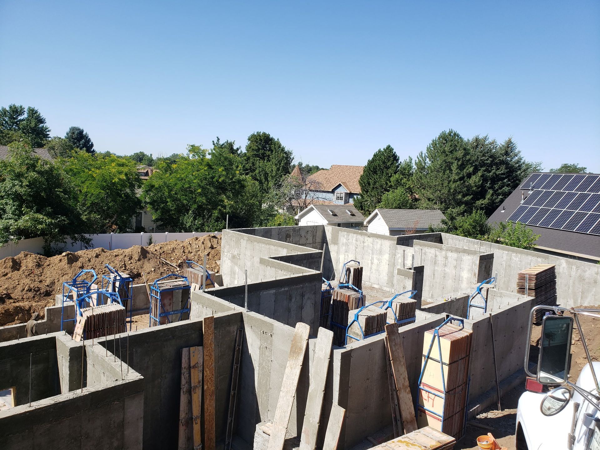 Construction site with concrete walls, workers, and solar panels under a clear blue sky