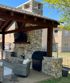 A patio with a table and chairs and a grill and fireplace.