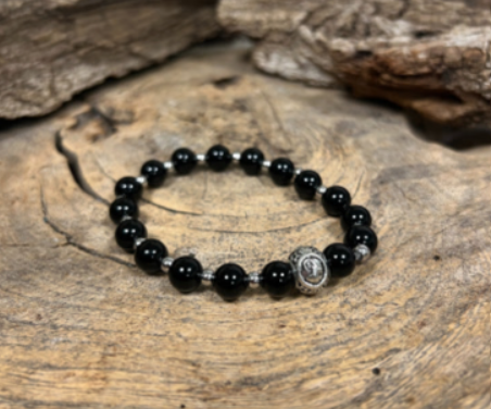 Armband met zwarte onyx kralen op kaartje met het symbool Steenbok en tekst in het Nederlands.