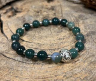 Bracelet with green beads and a Libra symbol; label reads