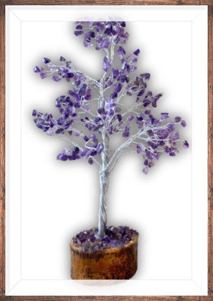 Amethistkristalboom met goudkleurige draadtakken in een houten pot, met daartussen bloemen en drijfhout.