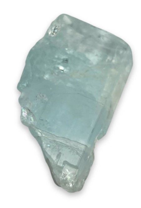 Lichtblauw aquamarijn kristal op een verweerd houten oppervlak, kleine bloemen vaag op de achtergrond.