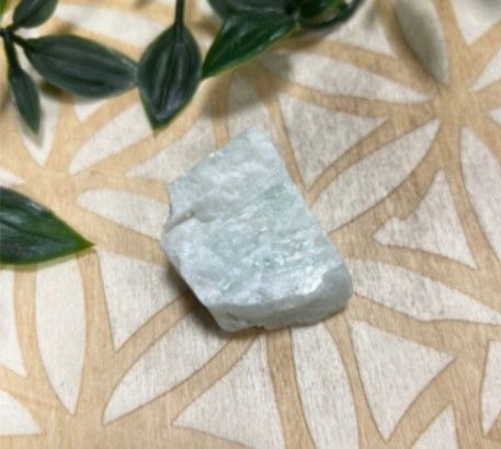 Groenachtig-geel gesteentemonster in een klein, wit, vierkant doosje.