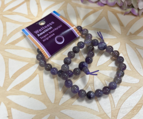 Donkerpaarse kralenarmband, waarschijnlijk van amethist, met een geknoopt kwastje.