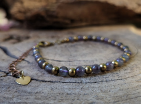 Armband met amethist kralen, gouden accenten en sluiting.