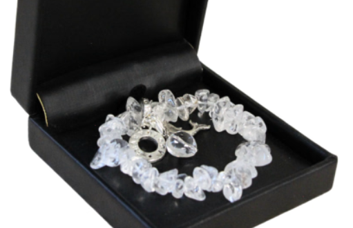 Armband met heldere, grove stenen in een zwart sieradendoosje op een houten oppervlak.