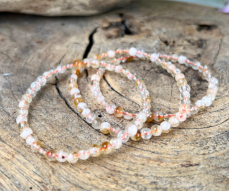 Kralenarmband met lichtoranje en heldere stenen.