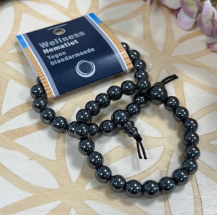 Armband van zwarte kralen, aan elkaar geregen en aan de bovenkant dichtgebonden met een zwart touwtje en een kraal.