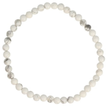 Ketting van witte howliet kralen op een houten oppervlak.