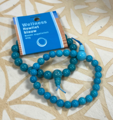 Armband van turquoise kralen met een grotere kraal en kwastje.