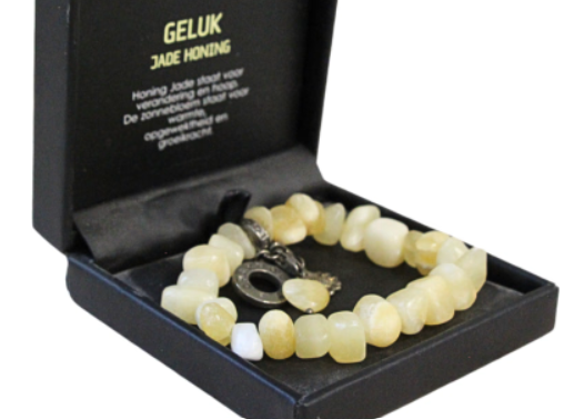 Armband van lichtgele stenen in een zwart doosje met inscriptie over verandering, hoop en warmte.