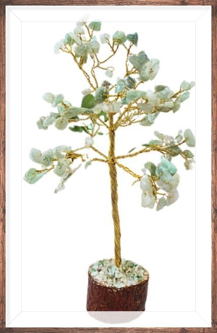 Sculptuur van een jadeboom op een houten sokkel, omlijst, met kunstbloemen en groen op de achtergrond.