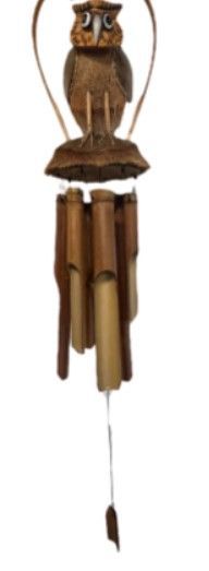 Windgong in de vorm van een uil, gemaakt van bamboe en kokosnootschil, hangt aan de muur.