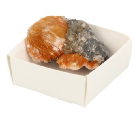 Mineraalmonster in een wit vierkant doosje; kleuren perzik, beige en grijs.