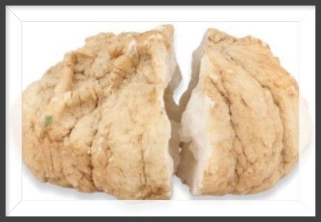 Close-up van een geode met een ruwe, witte buitenkant en een bruine, met kristallen gevulde binnenkant.