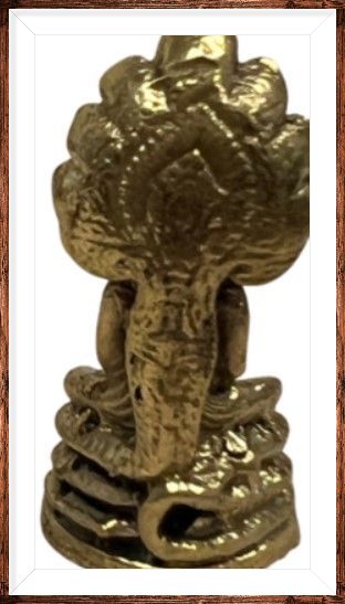 Een bronzen Boeddhabeeld, zittend op een houten oppervlak, beschut door een veelkoppige cobra.