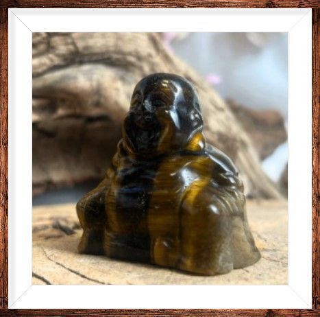 Beeld van lachende Boeddha, bruin en goud, met een witte omlijsting.