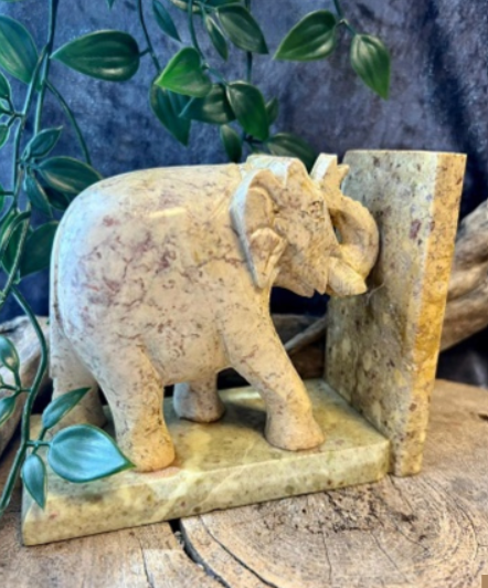 Twee tegenover elkaar staande stenen boekensteunen in de vorm van olifanten, beige en bruin, op een witte achtergrond.