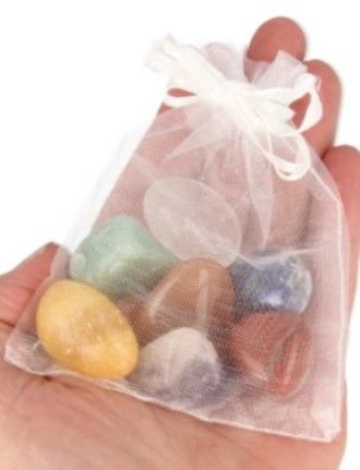 Zeven kleurrijke, getrommelde chakrastenen: geel, oranje, rood, groen, wit, blauw en paars.