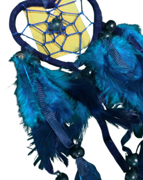 Blauwe dromenvanger in de vorm van een hart met veren hangt tegen een witte muur.