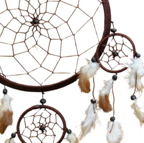 Bruine dromenvanger met veren en kralen, hangend tegen een witte muur.